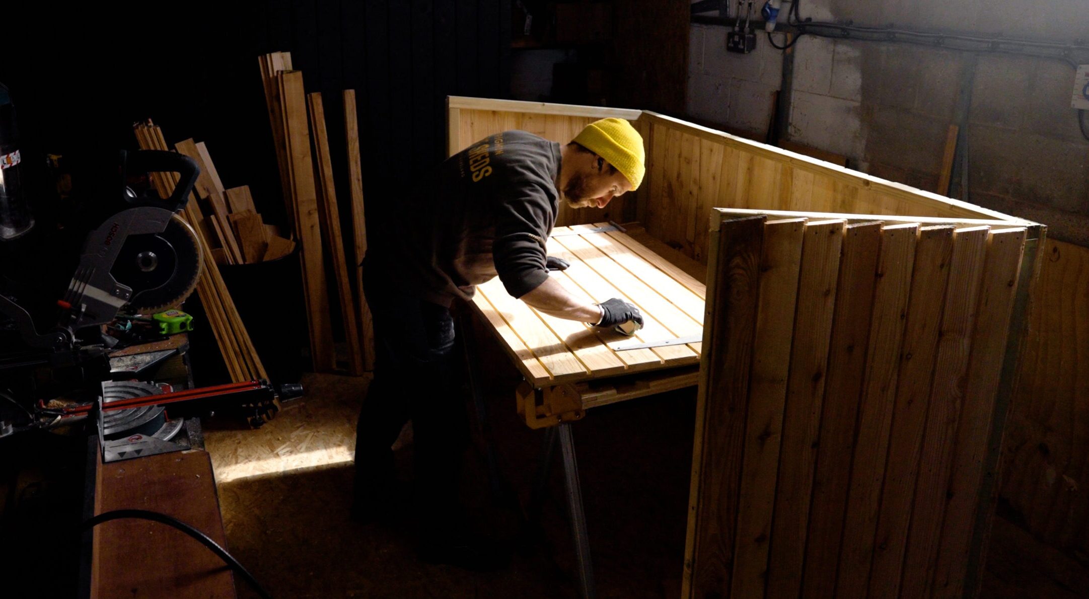 A man fitting a bike shed into a garden